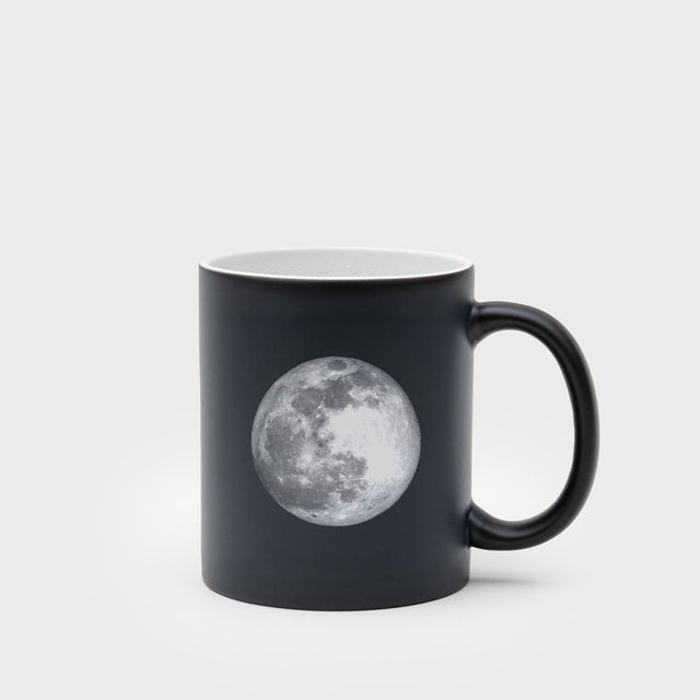 Black mug with a moon graphic on a light gray background