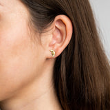 Close-up of an ear wearing a gold earring with a moon design.