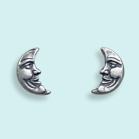 Silver moon-shaped earrings with faces on a light blue background