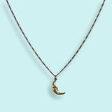 Gold crescent moon necklace on a light blue background