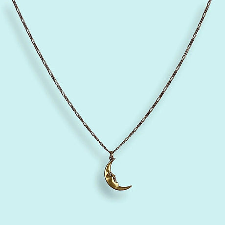 Gold crescent moon necklace on a light blue background