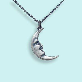 Silver moon-shaped pendant necklace on a light blue background