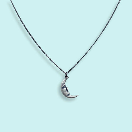 Crescent moon necklace on a light blue background