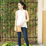 Woman wearing the gold fleck cork mini crossbody bag in front of a green ivy-covered wall.