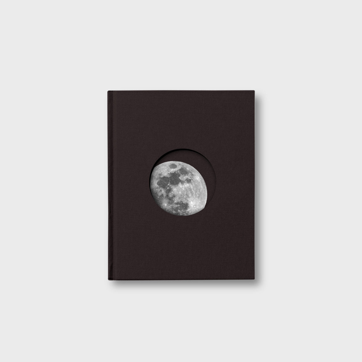 Black book with a circular cutout displaying the moon on a light gray background