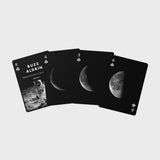 Playing cards with moon phases and astronaut imagery on a light gray background
