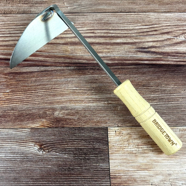 Sickle with wooden handle on a wooden surface