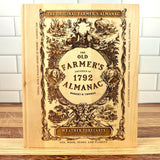 The Old Farmer's Almanac book on a wooden surface with a white tiled wall background