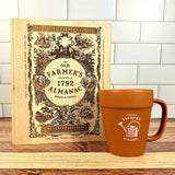 The Old Farmer's Almanac cutting board and a matching mug on a wooden surface with a white tiled wall background.