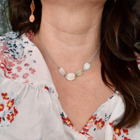 Necklace with hydrangea petal pendants worn by a person in a floral top