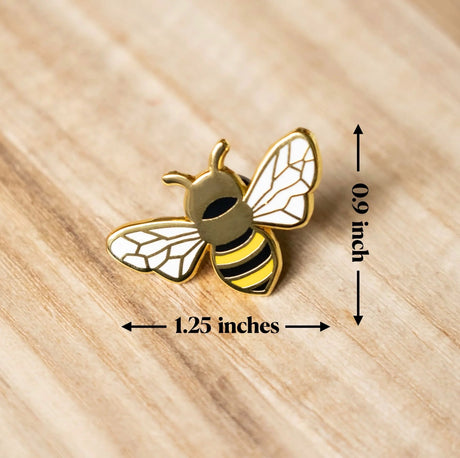 Bee-shaped pin with measurements on a wooden surface