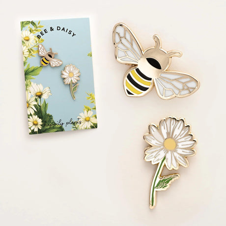 Enamel bee and daisy pins with a branded card on a white background