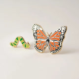 Butterfly and caterpillar pins on a light gray background