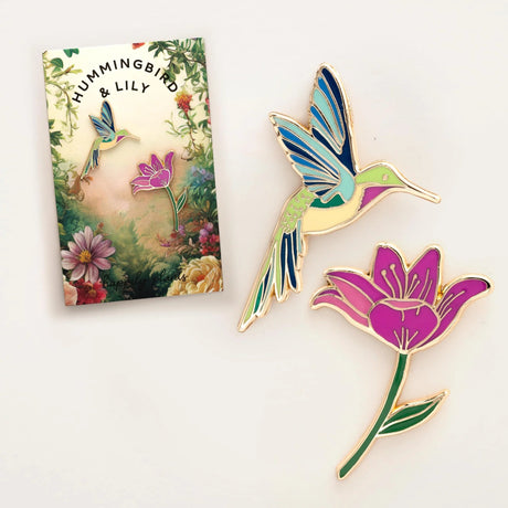 Colorful hummingbird and flower pins with a 'Hummingbird & Lily' branded box.