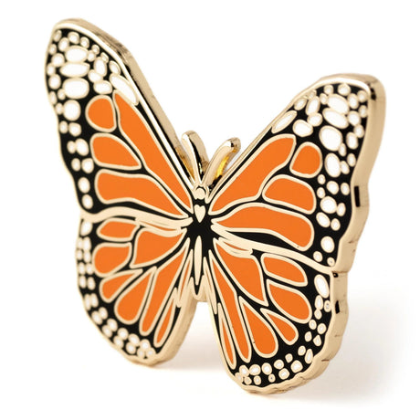 Butterfly-shaped enamel pin with orange and black pattern on a white background