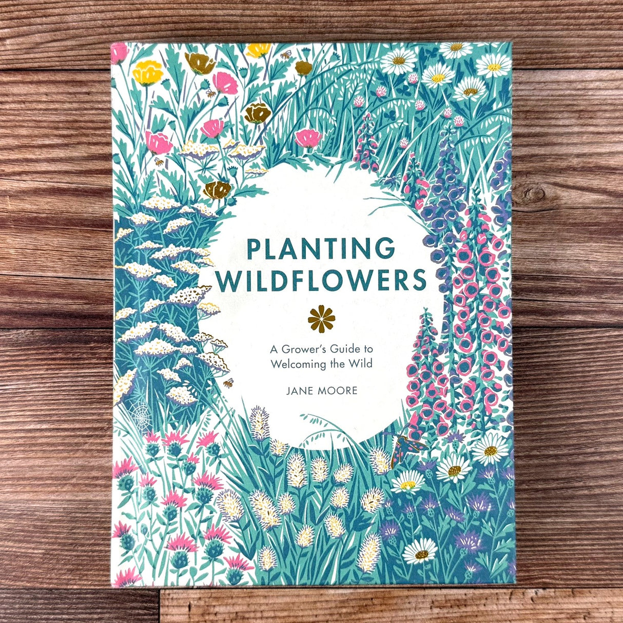 Book cover of 'Planting Wildflowers' by Jane Moore on a wooden surface