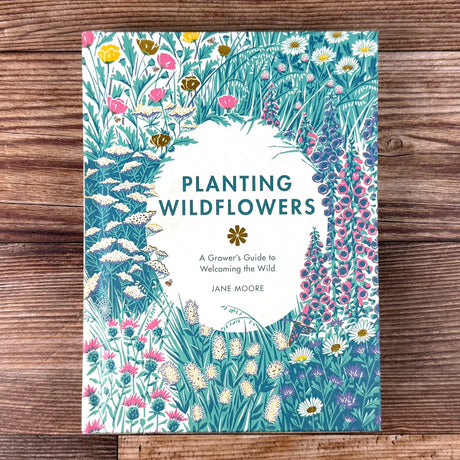 Book cover of 'Planting Wildflowers' by Jane Moore on a wooden surface