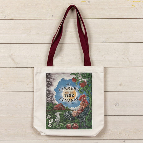 Tote bag with 'Old Farmer's Almanac' design with farm illustration with a rooster on a wooden surface