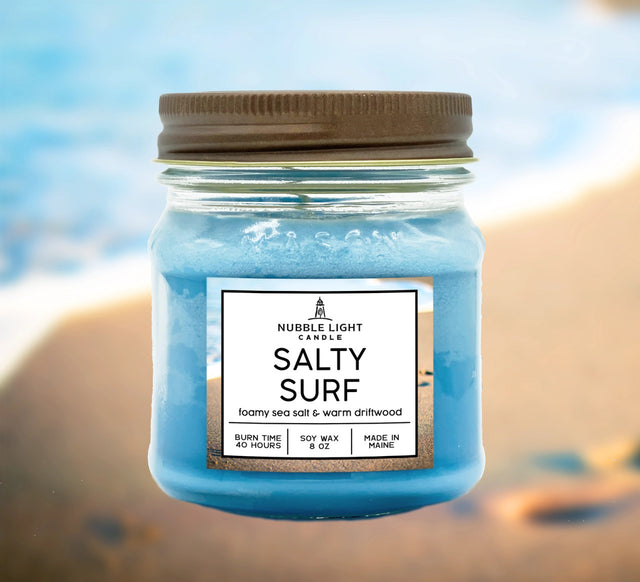 The Salty Surf candle jar shown against a beach background