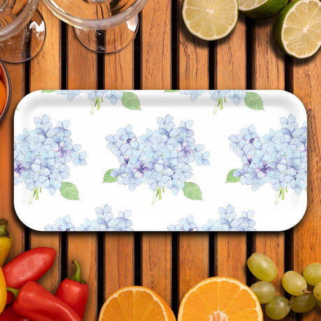 Floral-patterned tray on a wooden surface with fruits and vegetables.
