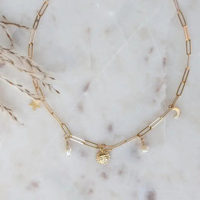 a gold paperclip chain with 14k gold fill charms of the sun, moon, and stars paired with delicate freshwater pearls