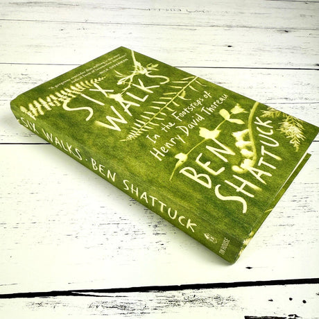 Six Walks book shown at a slight side angle on a white wood surface showing the spine of the book