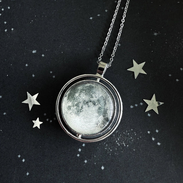 Necklace with a moon-phase pendant on a dark background with star decorations