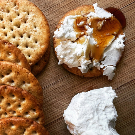 Crackers with a spread of cream cheese and honey on a wooden surface