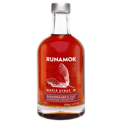 a clear glass bottle filled with rich amber colored maple syrup with a label graphic that reads "Runamok Maple Syrup Sugarmaker's Cut" with a graphic of a maple seedling