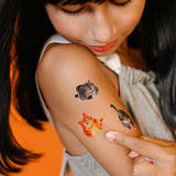Young girl with cat-themed temporary tattoos on her arm
