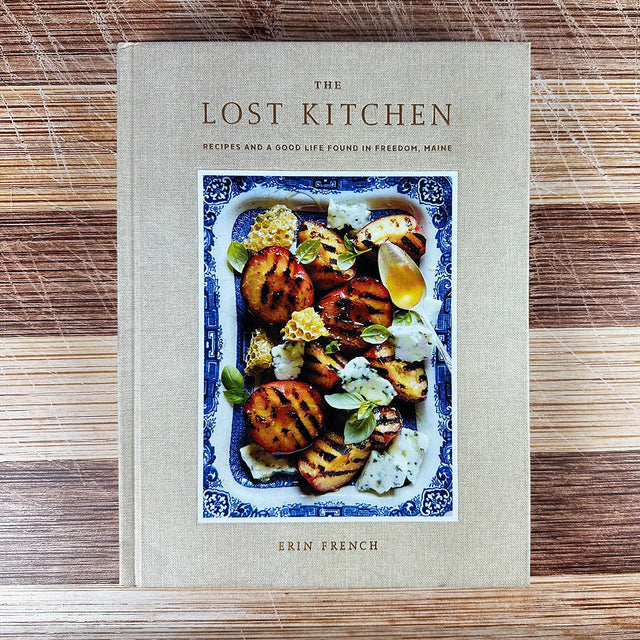Cookbook titled 'The Lost Kitchen' by Erin French on a wooden surface