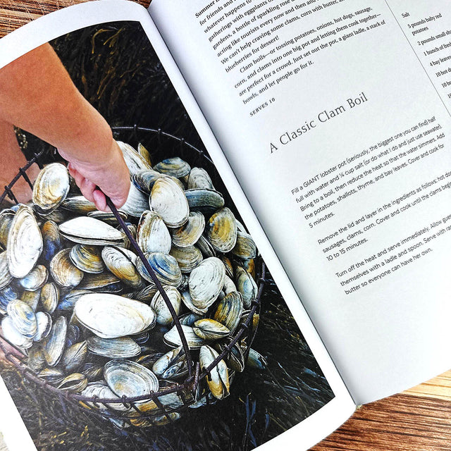 Open book with a hand holding clams and a recipe for a clam boil.