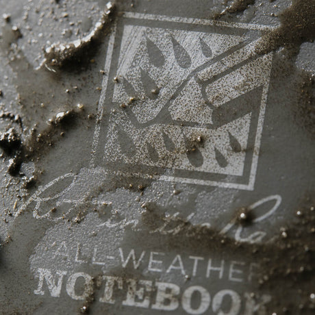 a close up of the top spiral notebook cover smeared with mud