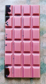 an unwrapped Ursa Major bar showing the brilliant pink hue of the raspberry white chocolate with swirls of dark chocolate and cacao nibs visible
