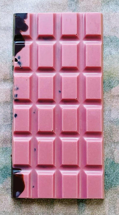 an unwrapped Ursa Major bar showing the brilliant pink hue of the raspberry white chocolate with swirls of dark chocolate and cacao nibs visible