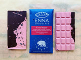 Three Ursa Major bars side by side. The center bar is in its royal blue wrapper with ursa major constellation illustration and the two surrounding bars are unwrapped and showing off their brilliant pink color swirled with dark chocolate and speckled with cacao nibs