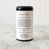 tin of Young Hyson tea showing the label on the back of the tea that details brewing tips along with history of the tea. Tin sits on a white marble surface with white background