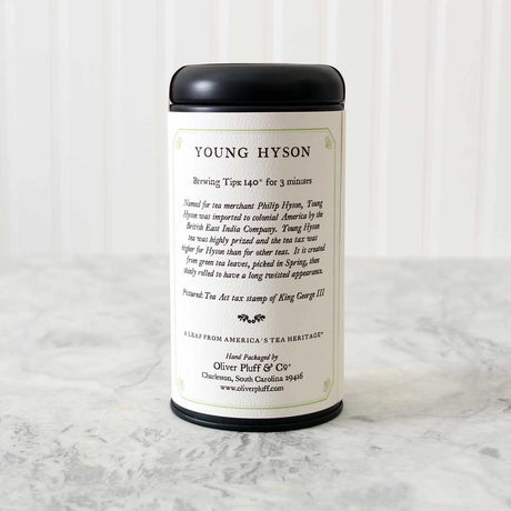 tin of Young Hyson tea showing the label on the back of the tea that details brewing tips along with history of the tea. Tin sits on a white marble surface with white background