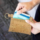 Person holding a cork keychain wallet with cards, blurred background