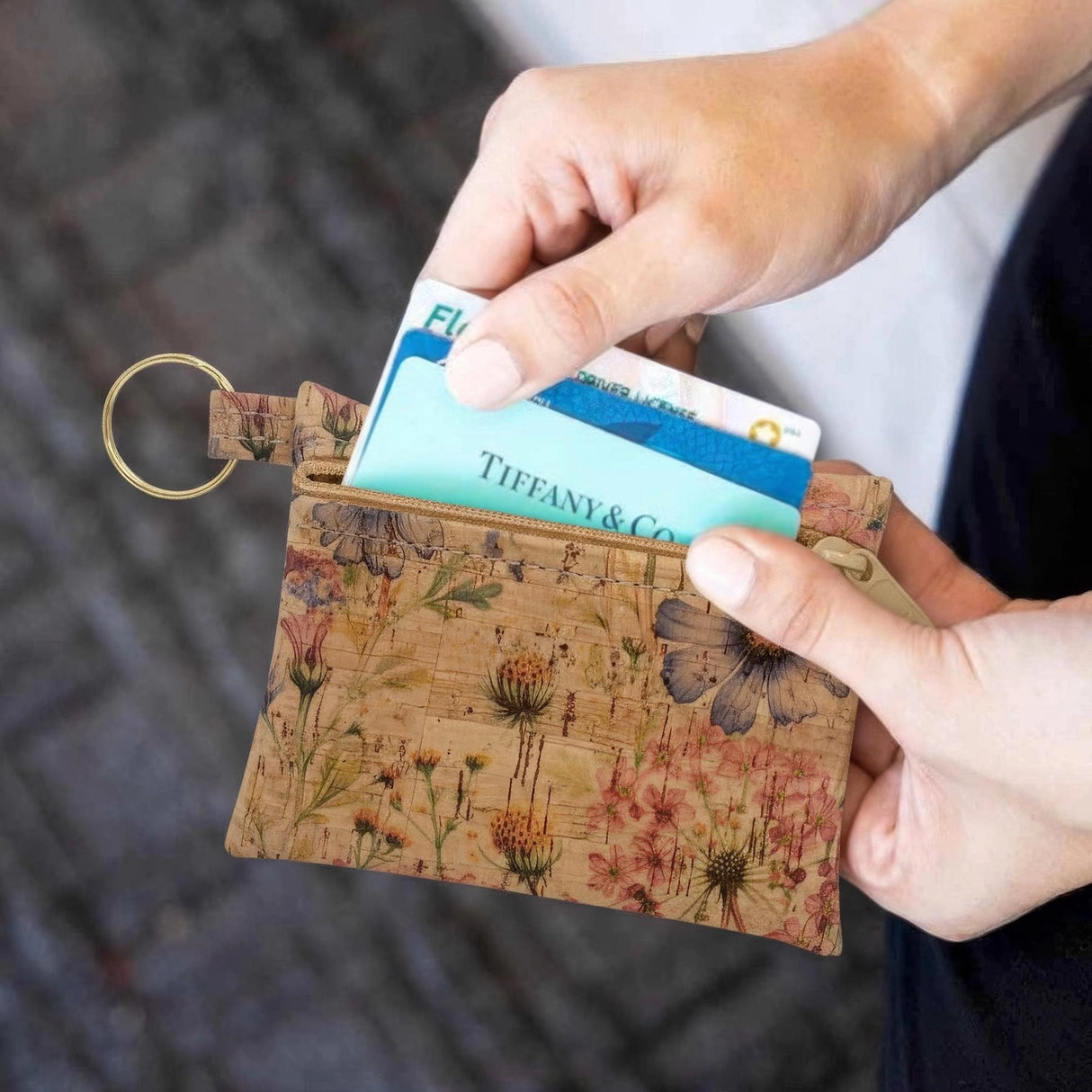 Floral-patterned cardholder with a Tiffany & Co. card being inserted, held by a person.