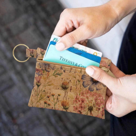 Floral-patterned cardholder with a Tiffany & Co. card being inserted, held by a person.