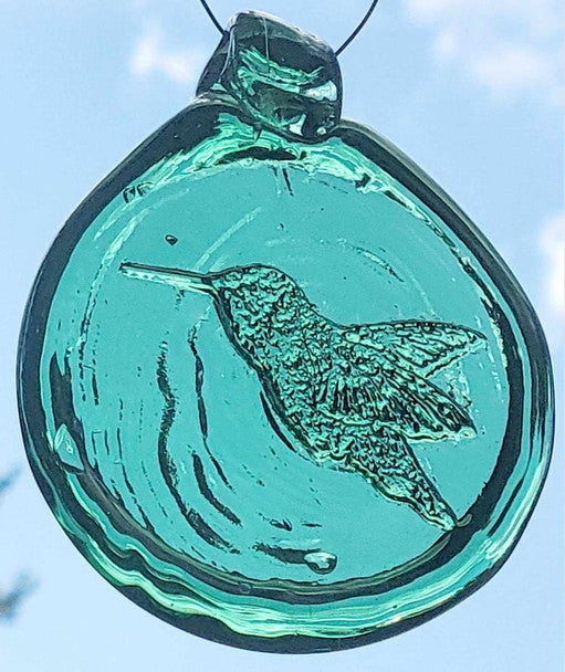 a teal green, round glass suncatcher with a relief image of a hummingbird