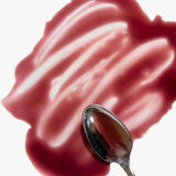 Blueberry lemon maple syrup in a purpleish smear on a white surface with a spoon