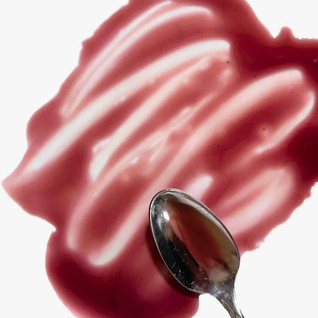 Blueberry lemon maple syrup in a purpleish smear on a white surface with a spoon