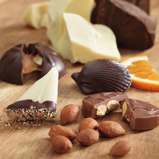 Assorted chocolate-dipped treats and almonds on a wooden surface