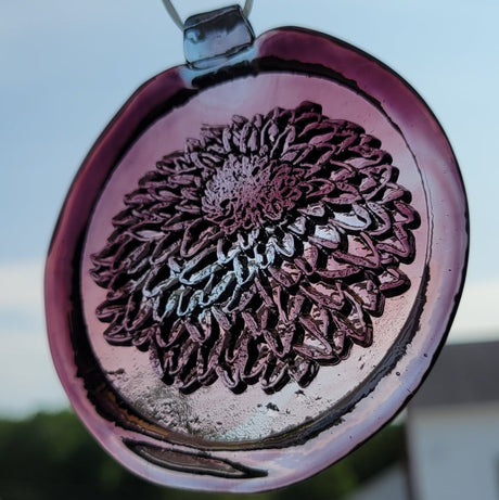 Glass suncatcher with a chrysanthemum flower design shown in light purple to better see the design.