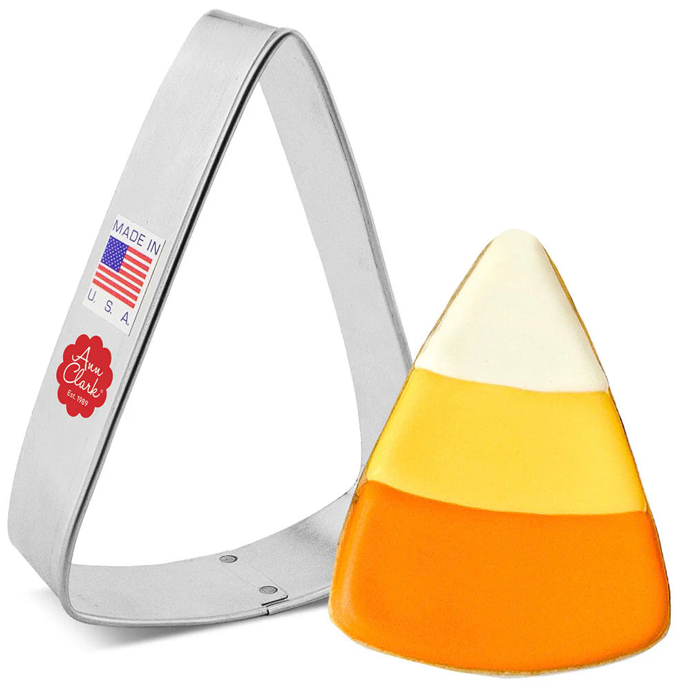 a triangle wedge cookie cutter next to a fully decorated cookie made to look like candy corn