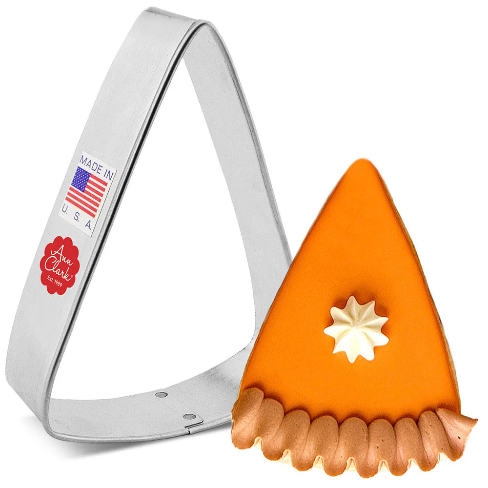 a triangle wedge cookie cutter next to a fully decorated cookie made to look like a slice of pumpkin pie with pie crust and a dollop of whipped cream