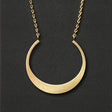 A gold necklace with a crescent moon pendant
