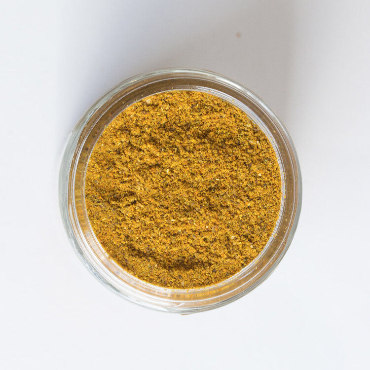 a top down view of an open jar of the comfort curry showing the rich, golden yellow hue of the spice blend